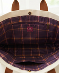 Caki Lawrence woven label on the Parlor Satchel's purple plaid lining with interior zip pocket