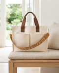 The Parlor Satchel in Garden Club — cream canvas bag with brown handles and antique gold lettered crossbody strap